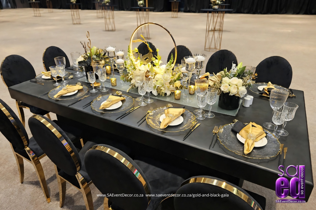 Black table with matching chairs with Glowing gold hoop white rose centrepiece designed by SA Event Decor